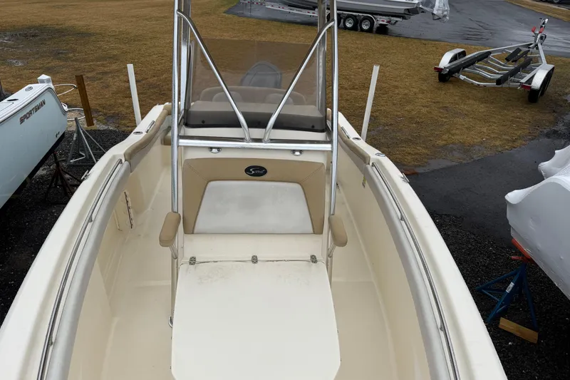 Slide: The Image of 2014 Scout 210 XSF boat interior with seating and console, parked on grass. - 8