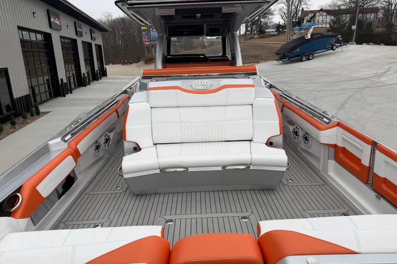 Slide: The Image of 2024 Nor-Tech 500 Sport Center Console with orange and white seating, docked near a garage. - 15