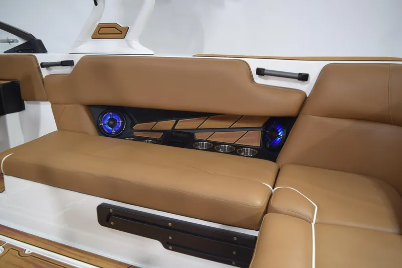 Slide: The Image of 2026 Moomba Tykon boat interior with tan seating, cup holders, and blue LED speakers. - 15