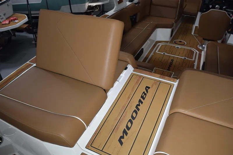 Slide: The Image of 2026 Moomba Tykon boat interior with brown leather seating and branded flooring. - 16