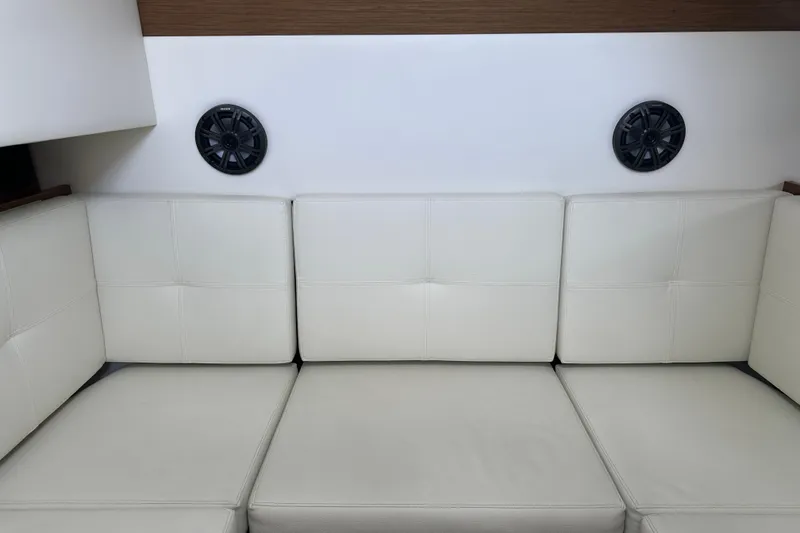 Slide: The Image of 2019 Cruisers Yachts 338 Outboard interior with white cushioned seating and wood accents. - 24