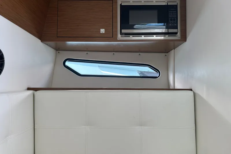 Slide: The Image of 2019 Cruisers Yachts 338 Outboard interior with white cushioned seating and wooden paneling. - 27