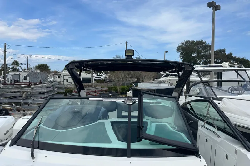 Slide: The Image of 2019 Cruisers Yachts 338 Outboard boat with open windshield, docked under blue sky. - 10