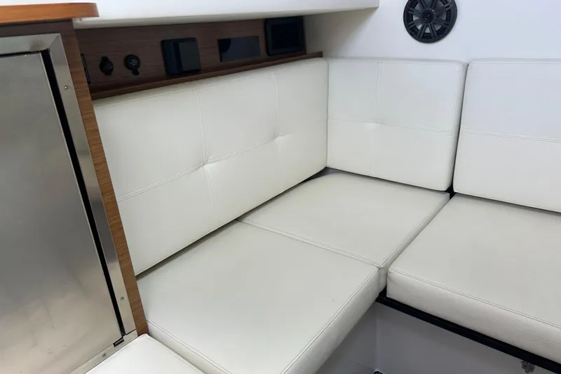 Slide: The Image of 2019 Cruisers Yachts 338 Outboard interior with white cushioned seating and wood accents. - 23