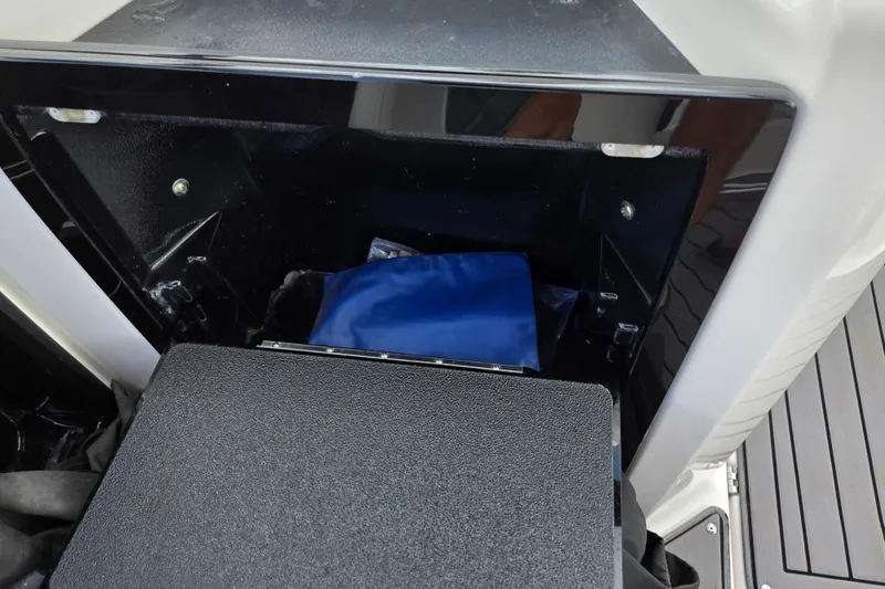 Slide: The Image of Storage compartment in 2018 Yamaha Boats 212X, featuring a blue bag inside. - 11