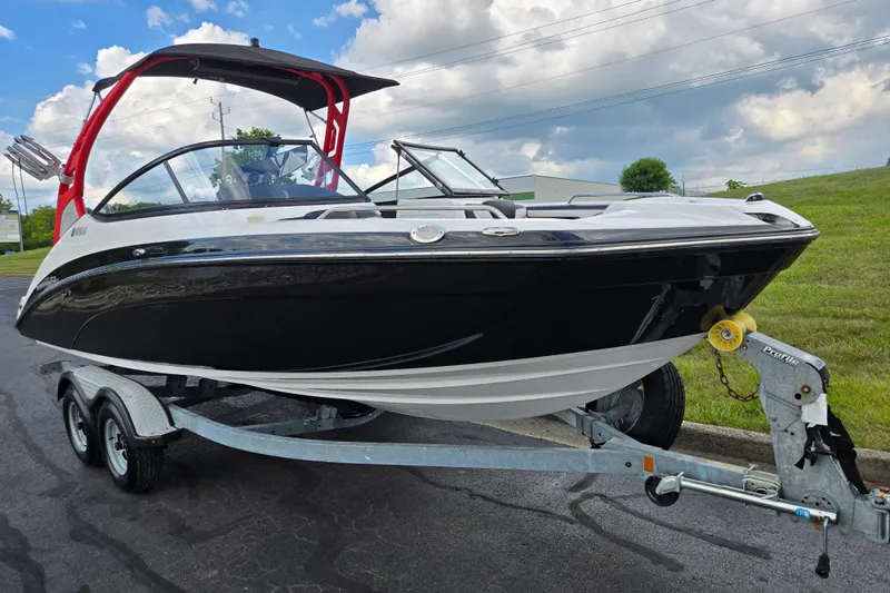 Slide: The Image of 2018 Yamaha Boats 212X on trailer, black and white design, red wakeboard tower, parked outdoors. - 5