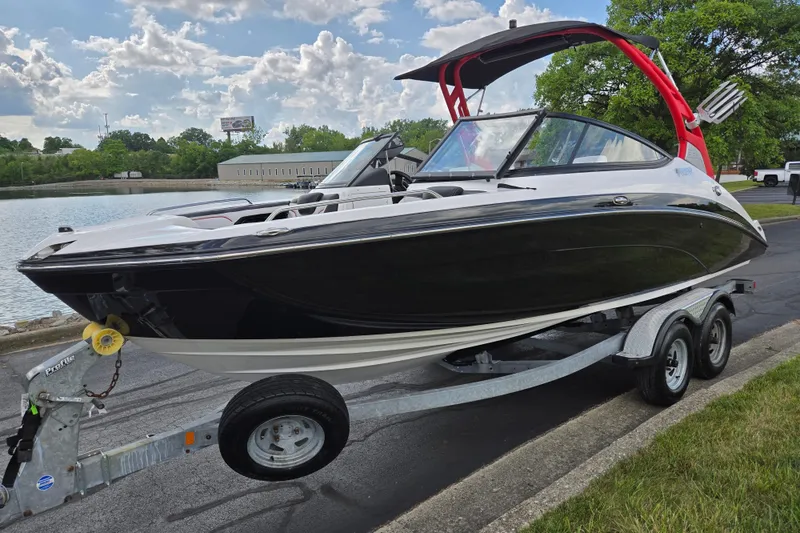 Slide: The Image of 2018 Yamaha Boats 212X on trailer by a lake, featuring sleek black design. - 8