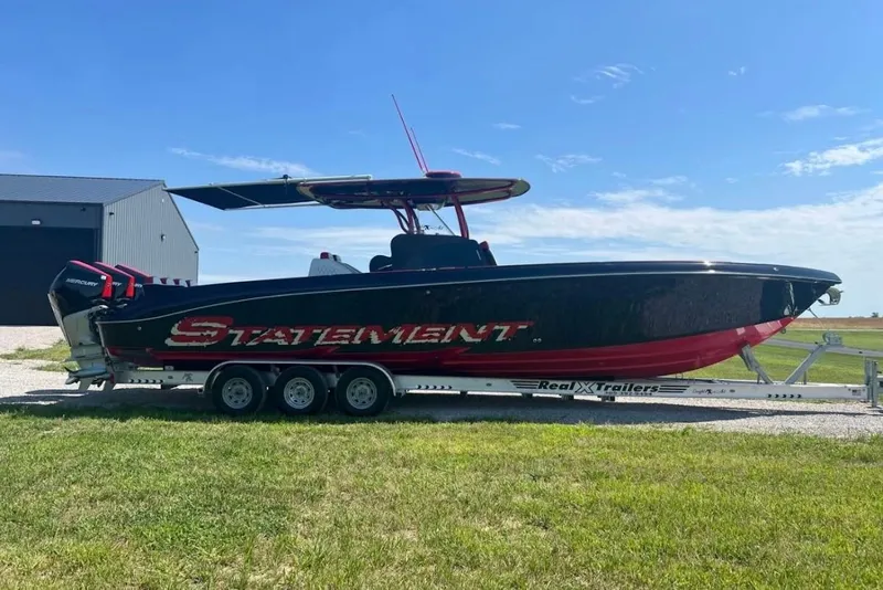 Slide: The Image of 2018 Statement 380 Open boat on trailer, black and red design, parked outdoors. - 0
