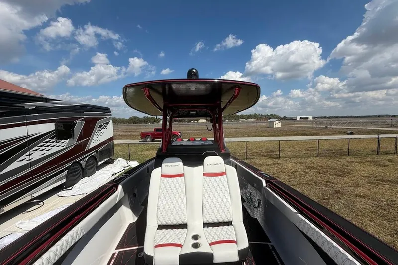 Slide: The Image of 2018 Statement 380 Open boat with white seating, parked near RV under blue sky. - 25