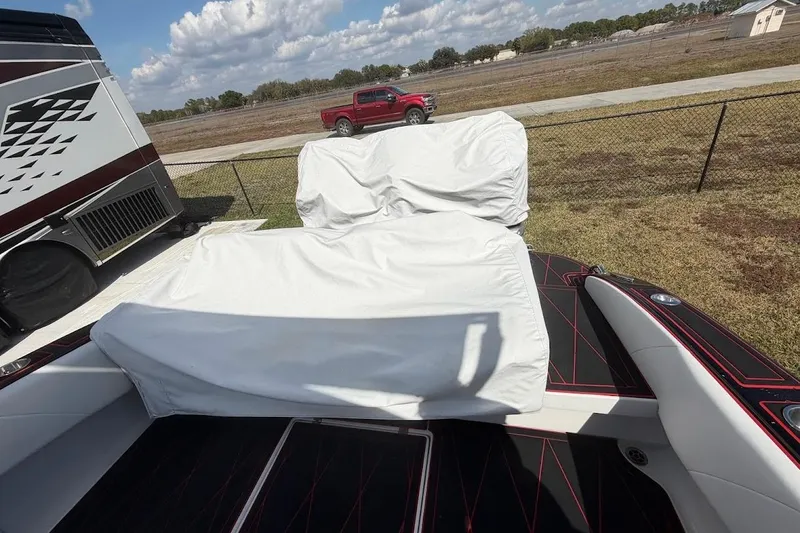 Slide: The Image of 2018 Statement 380 Open boat with covered seating, parked near a red truck and RV. - 29