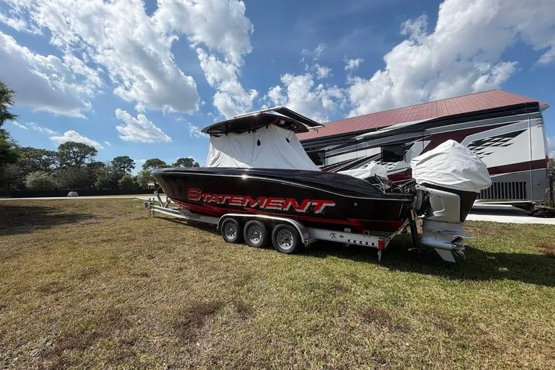 Slide: The Image of 2018 Statement 380 Open boat on trailer, parked on grass under a partly cloudy sky. - 32