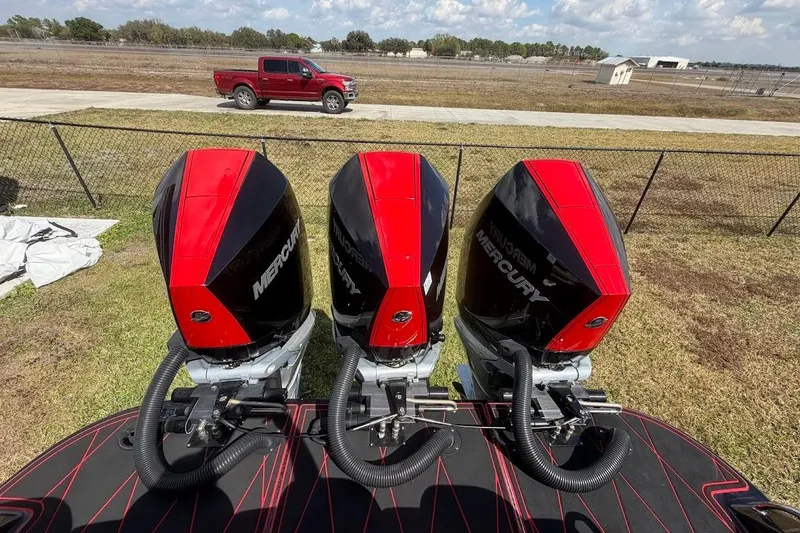 Slide: The Image of Three Mercury outboard engines on a 2018 Statement 380 Open boat, with a red truck in the background. - 35