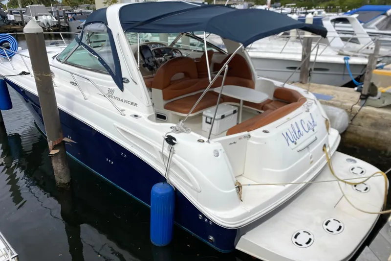 Slide: The Image of 2004 Sea Ray 380 Sundancer docked, featuring a blue canopy and spacious seating area. - 1