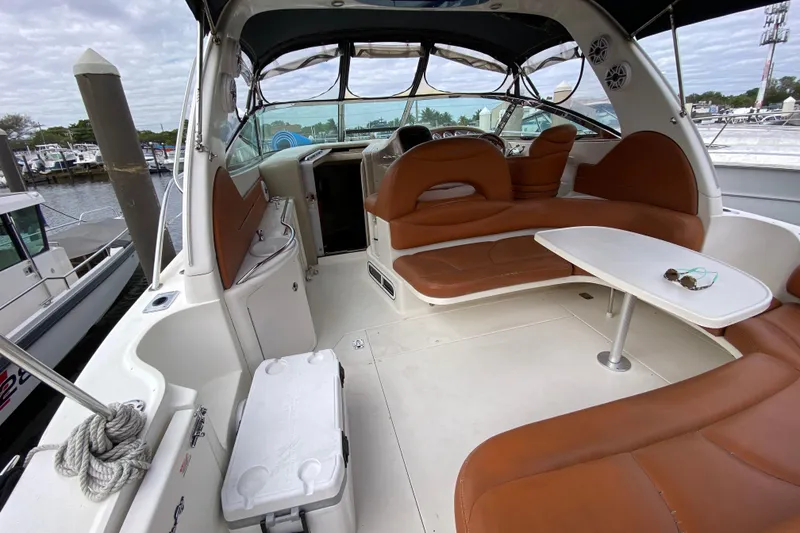 Slide: The Image of 2004 Sea Ray 380 Sundancer interior with brown seating and white table, docked at marina. - 8