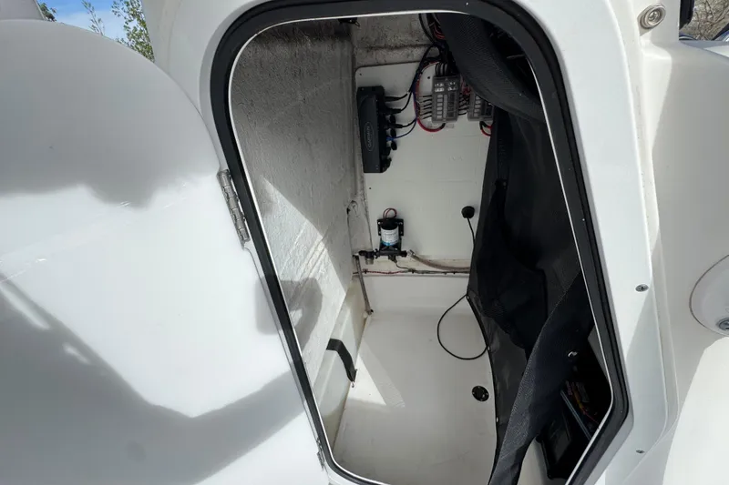 Slide: The Image of 2022 Sportsman Open 212 Center Console interior storage compartment with wiring and equipment. - 47