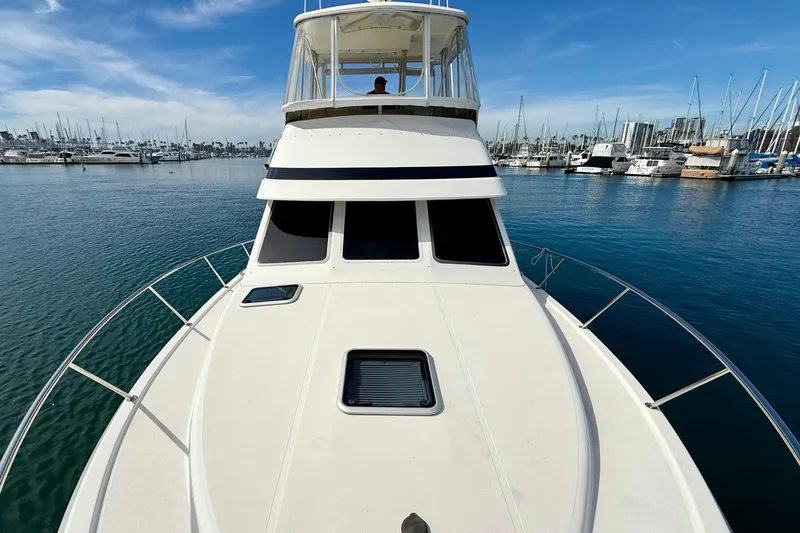 Slide: The Image of 1998 Riviera 34 Convertible yacht docked in a marina under a clear blue sky. - 14
