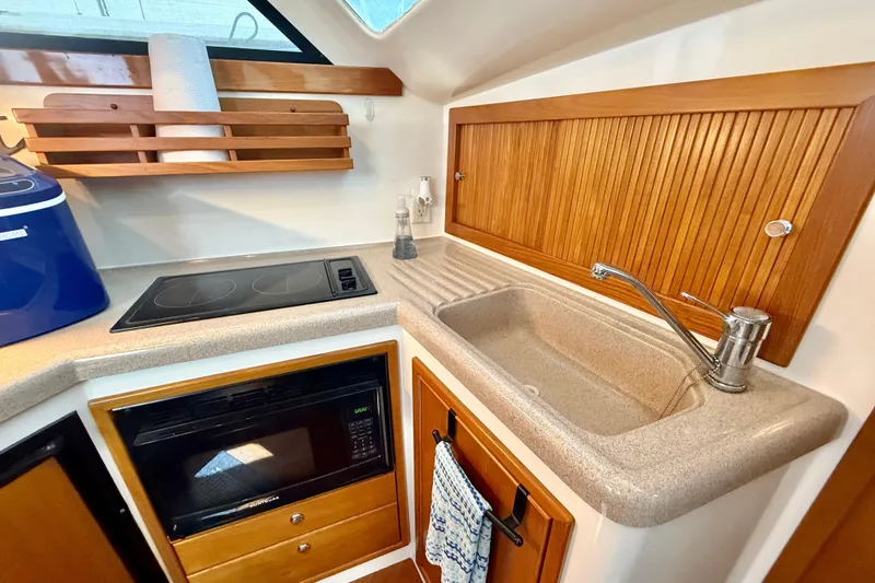 Slide: The Image of 1998 Riviera 34 Convertible yacht kitchen with sink, stove, and microwave. - 22