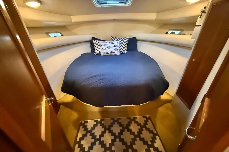 Slide: The Image of Cozy cabin interior of 1998 Riviera 34 Convertible yacht with blue bedding and patterned rug. - 27
