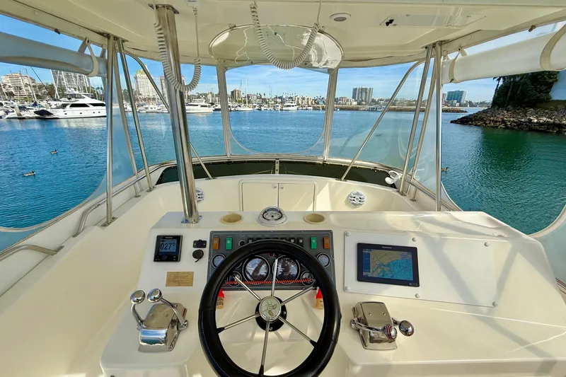 Slide: The Image of Cockpit view of 1998 Riviera 34 Convertible yacht with marina backdrop. - 6