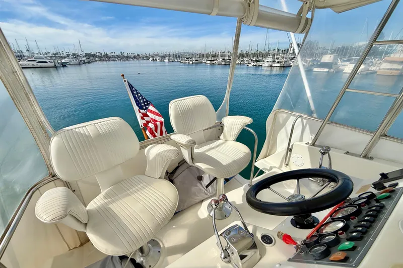 Slide: The Image of Cockpit of 1998 Riviera 34 Convertible yacht with American flag, marina view. - 9