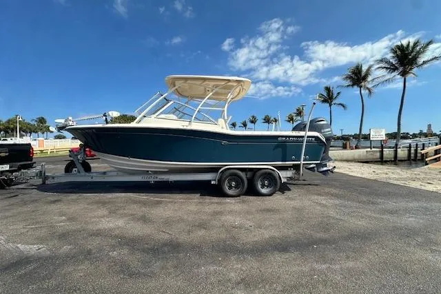 Slide: The Image of 2018 Grady-White Freedom 255 boat on trailer, parked near palm trees under blue sky. - 6