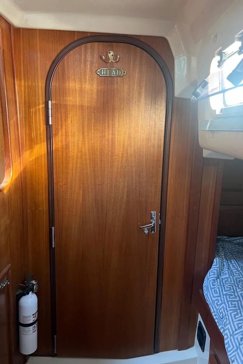 Slide: The Image of Wooden cabin door inside 1992 Hunter 43 sailboat, featuring a fire extinguisher nearby. - 14
