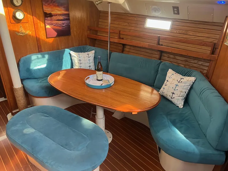Slide: The Image of Cozy 1992 Hunter 43 yacht interior with blue seating, wooden table, and nautical decor. - 3