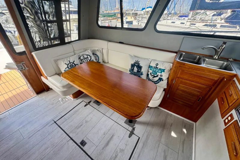 Slide: The Image of Cozy interior of 1989 Mediterranean 38 yacht with wooden table, white seating, and kitchenette. - 11