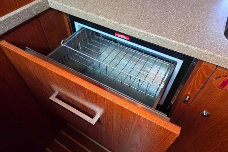 Slide: The Image of Wooden cabinet with open drawer revealing a built-in refrigerator on a 2012 Tiara Yachts 3900 Open. - 24