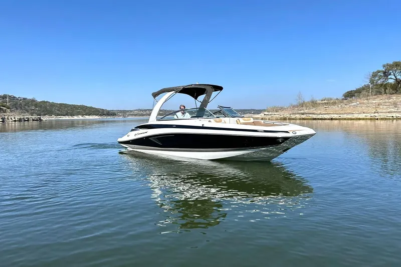 Slide: The Image of 2019 Crownline Eclipse E285 boat cruising on a calm lake under a clear blue sky. - 10