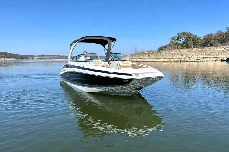 Slide: The Image of 2019 Crownline Eclipse E285 boat cruising on a calm lake under a clear blue sky. - 11