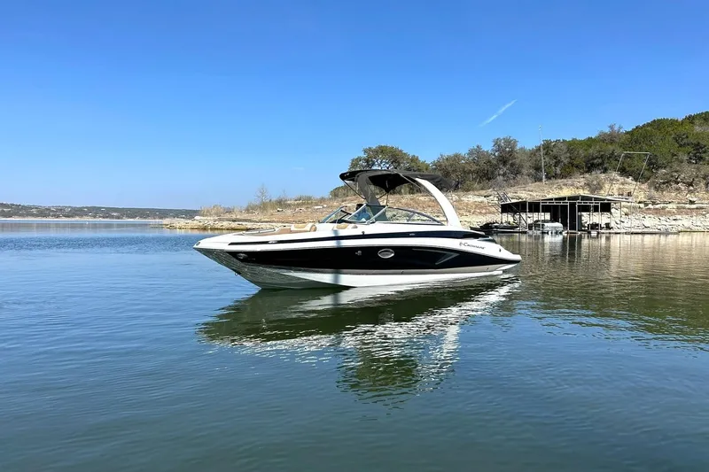 Slide: The Image of 2019 Crownline Eclipse E285 boat on a serene lake under a clear blue sky. - 14