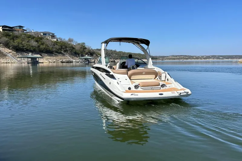 Slide: The Image of 2019 Crownline Eclipse E285 boat cruising on a serene lake under a clear blue sky. - 19