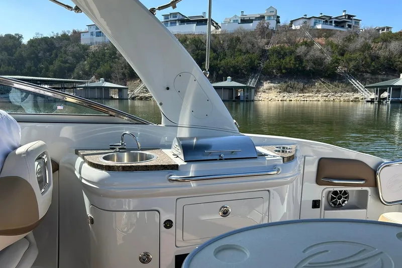 Slide: The Image of 2019 Crownline Eclipse E285 boat interior with sink and grill, docked by scenic waterfront. - 29