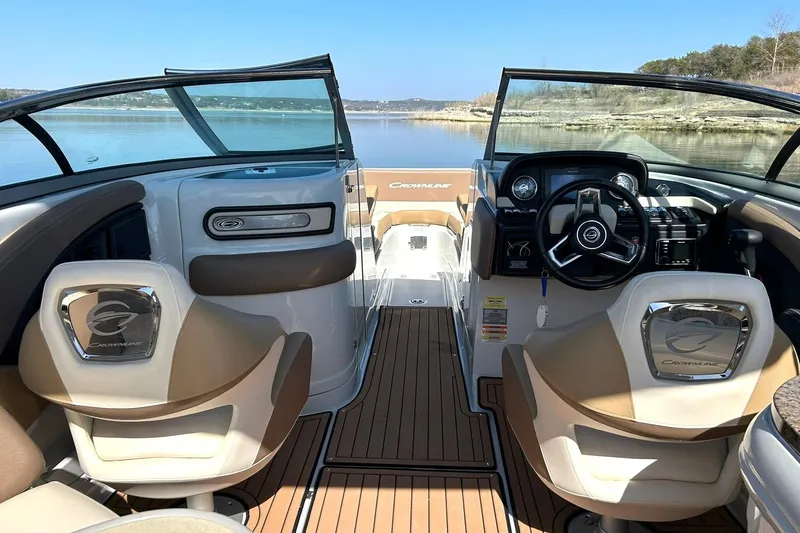 Slide: The Image of 2019 Crownline Eclipse E285 boat interior with steering wheel and seating, on a calm lake. - 32