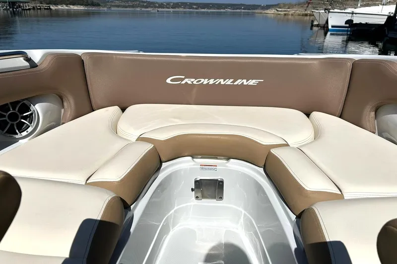 Slide: The Image of 2019 Crownline Eclipse E285 boat interior with beige and white seating, docked by a serene lake. - 41