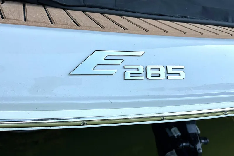 Slide: The Image of 2019 Crownline Eclipse E285 boat emblem on sleek white surface. - 49