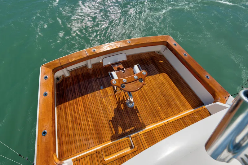 Slide: The Image of 2002 Viking Convertible yacht with polished wooden deck and fishing chair on calm water. - 12