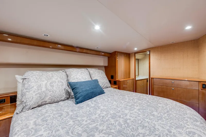 Slide: The Image of Luxurious bedroom interior of 2002 Viking Convertible yacht with elegant bedding and wood cabinetry. - 26