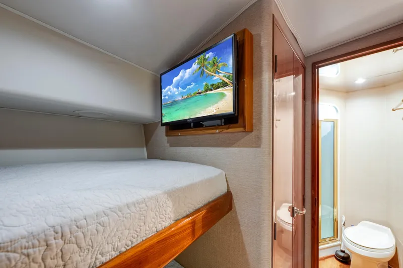 Slide: The Image of 2002 Viking Convertible yacht cabin with bed, wall-mounted TV, and adjacent bathroom. - 29