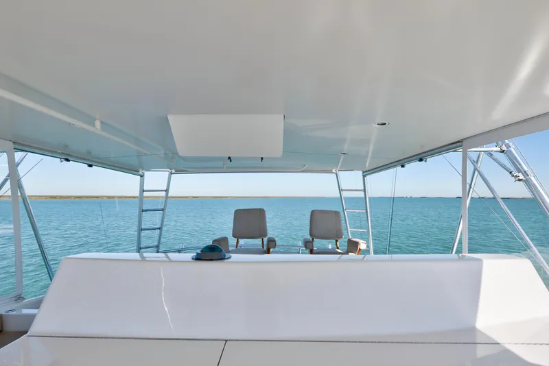 Slide: The Image of 2002 Viking Convertible yacht helm with ocean view, featuring dual captain chairs and ladders. - 8