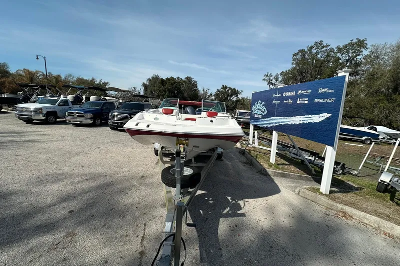 Slide: The Image of 2016 Hurricane SunDeck 187 OB boat on trailer in parking lot with dealership sign. - 4