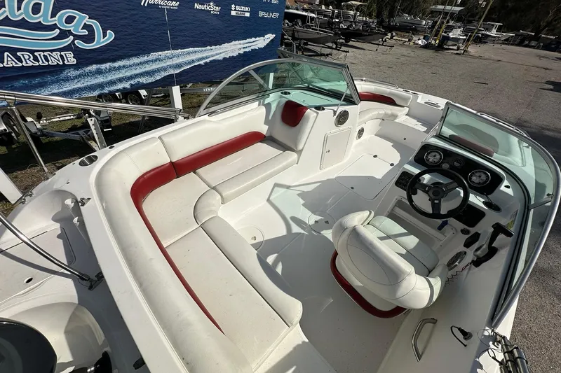 Slide: The Image of 2016 Hurricane SunDeck 187 OB boat interior with white and red seating, steering console, and spacious layout. - 9