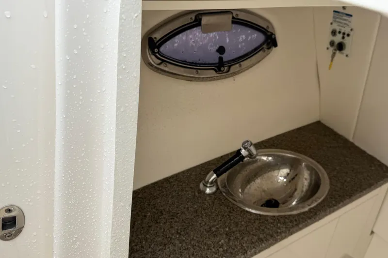 Slide: The Image of 2024 Robalo R317 Dual Console boat interior with sink and porthole window. - 14