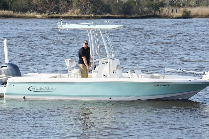 Slide: The Image of 2020 Robalo 226 Cayman boat on water with a person standing at the helm. - 7