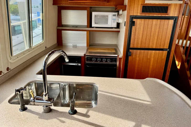 Slide: The Image of 2004 Nordic Tug 42 galley with sink, stove, microwave, and wooden cabinetry. - 14