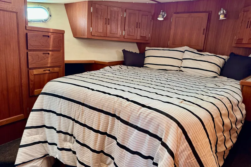 Slide: The Image of Cozy bedroom in 2004 Nordic Tug 42 with striped bedding and wooden cabinetry. - 15