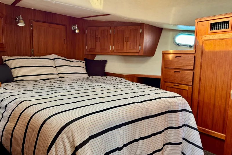 Slide: The Image of Cozy bedroom in 2004 Nordic Tug 42 with wood cabinetry and striped bedding. - 16