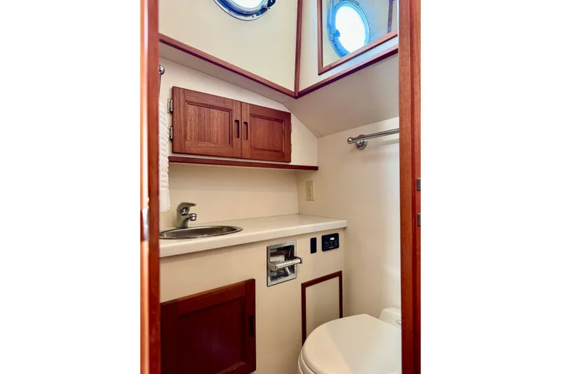 Slide: The Image of 2004 Nordic Tug 42 bathroom with wooden cabinets, sink, and porthole window. - 19