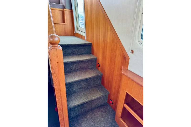 Slide: The Image of Interior stairs of 2004 Nordic Tug 42, featuring wooden paneling and carpeted steps. - 25